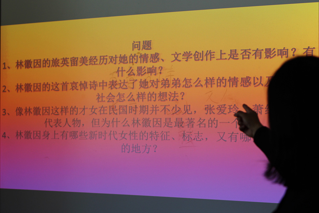 A professors points to a presentation displaying Chinese characters.